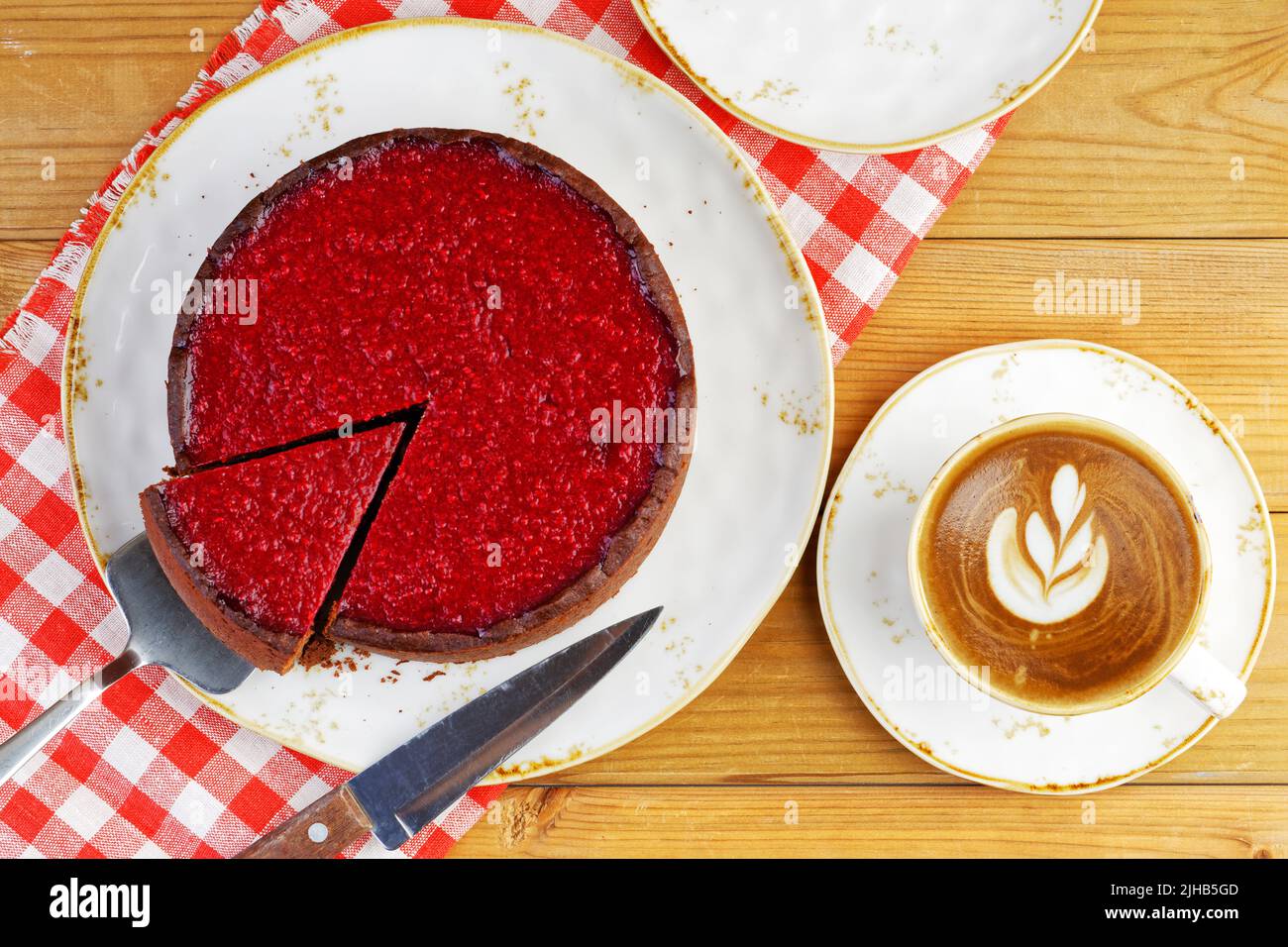 Homemade raspberry and strawberry cheesecake and cup of coffee cappuccino on wooden table. Top view. Stock Photo