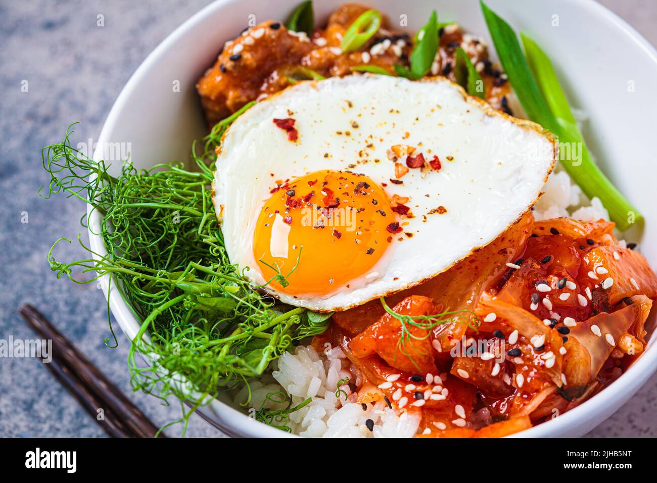 Bibimbap - meat, rice, kimchi, egg and sprouts in a white bowl. Traditional Korean food. Stock Photo
