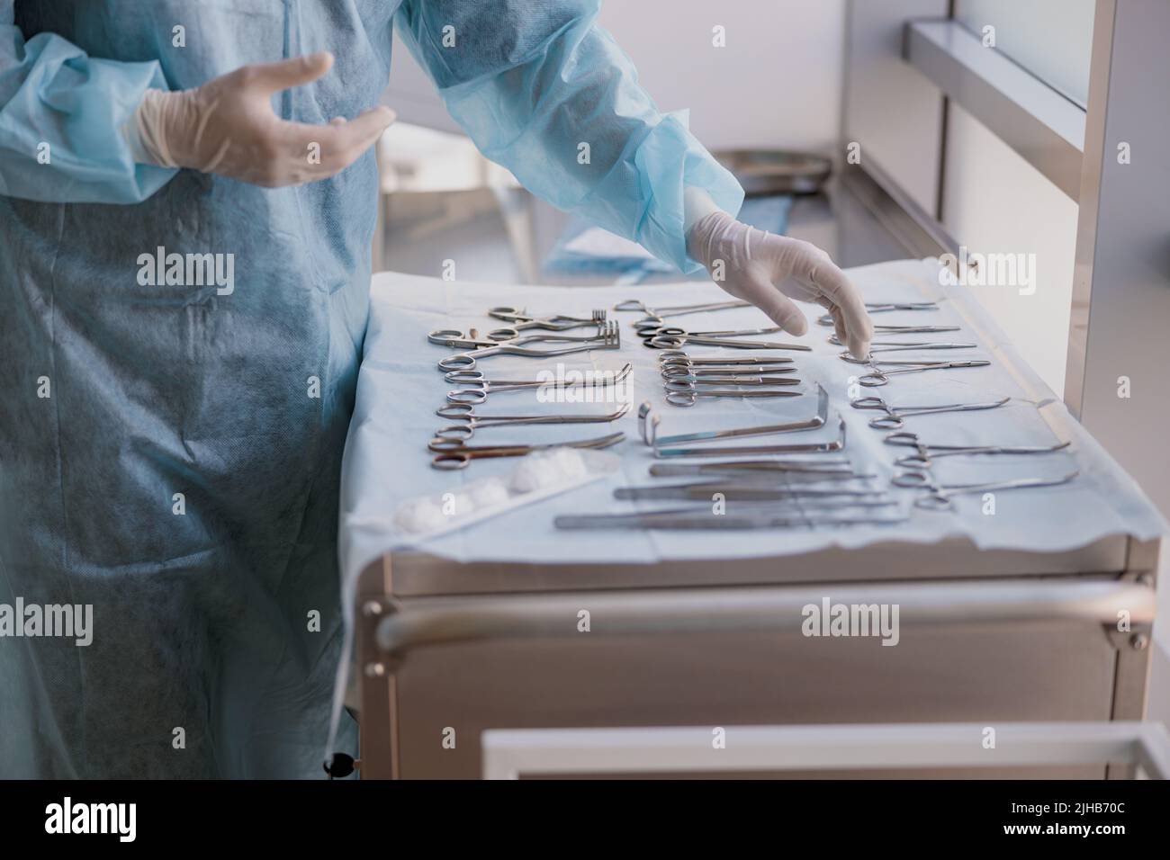 Nurse hand taking surgical instruments from table for a surgery during operation Stock Photo