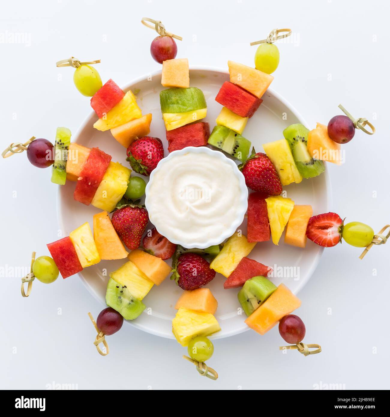 A platter of fresh fruit skewers isolated against a white background