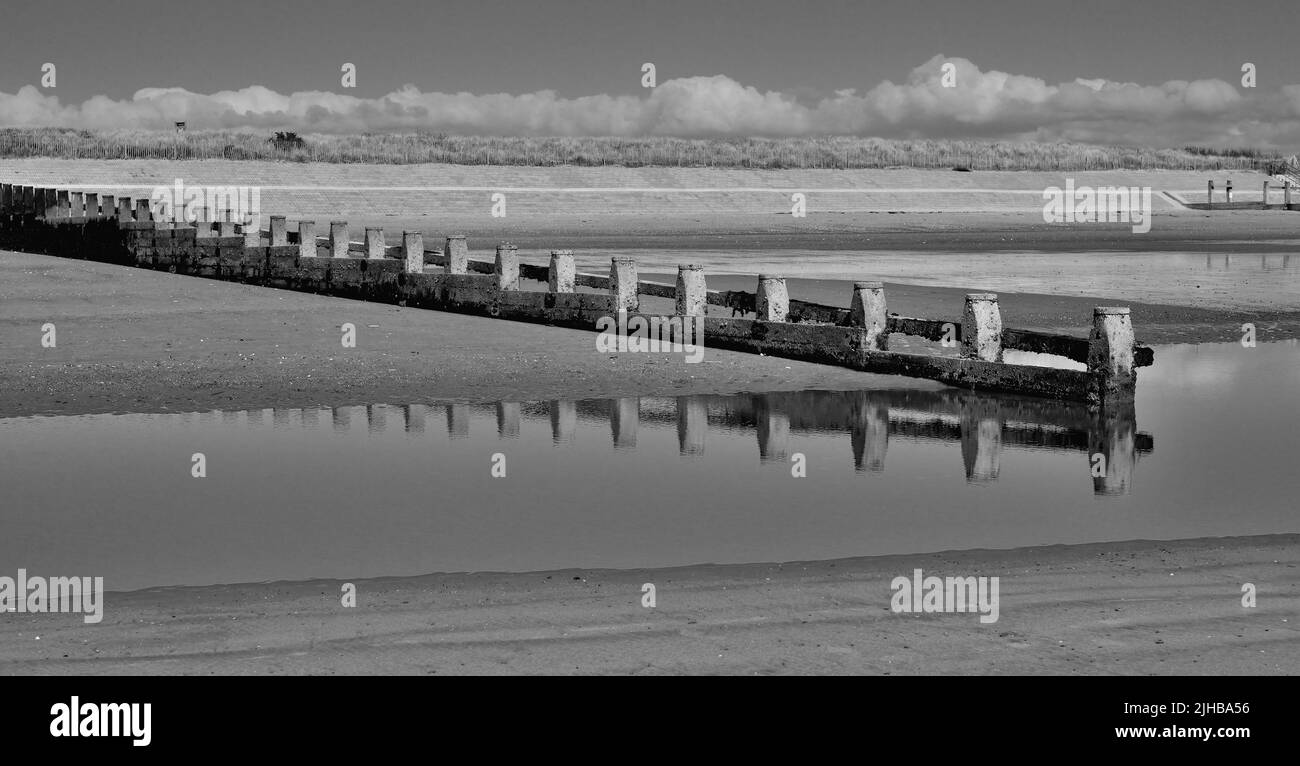 Groynes on the beach at Dawlish Warren, South Devon, at low tide (processed as a black and white image). Stock Photo