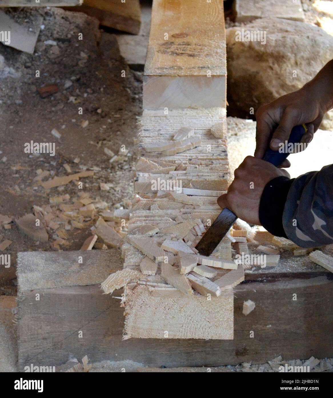 Carpenter working with a chisel in a wooden beam Stock Photo