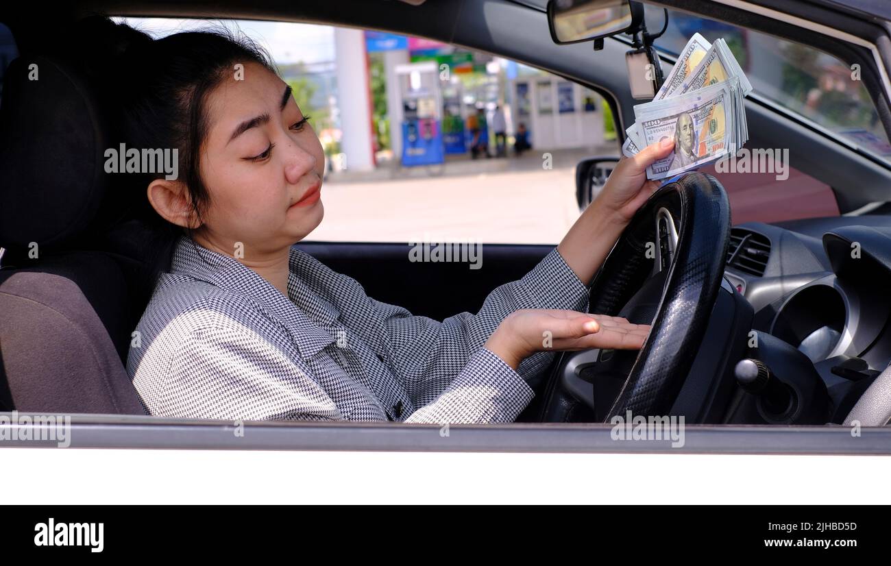 Desperate woman hold cash dollar bills next to car with an open tank