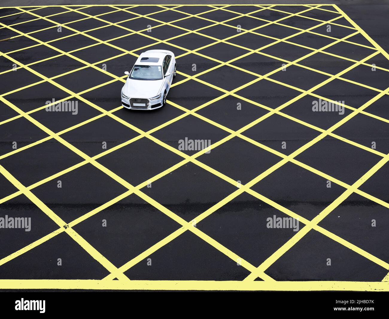 A car drive through the asphalt road which painted in Yellow line geometric shape square grid pattern of line marking Stock Photo