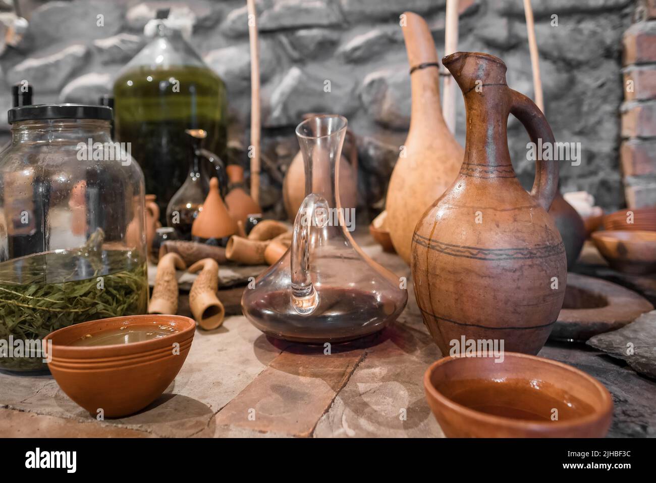 Young wine in clay bowl next to vintage georgian terracotta jug in authentic Georgian wine cellar. Stock Photo