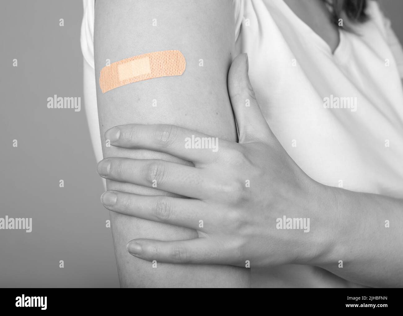 Woman arm with medical plaster. Vaccination, antiviral injection, vaccine-preventable diseases, health care and medicine concept. Black and white. High quality photo Stock Photo