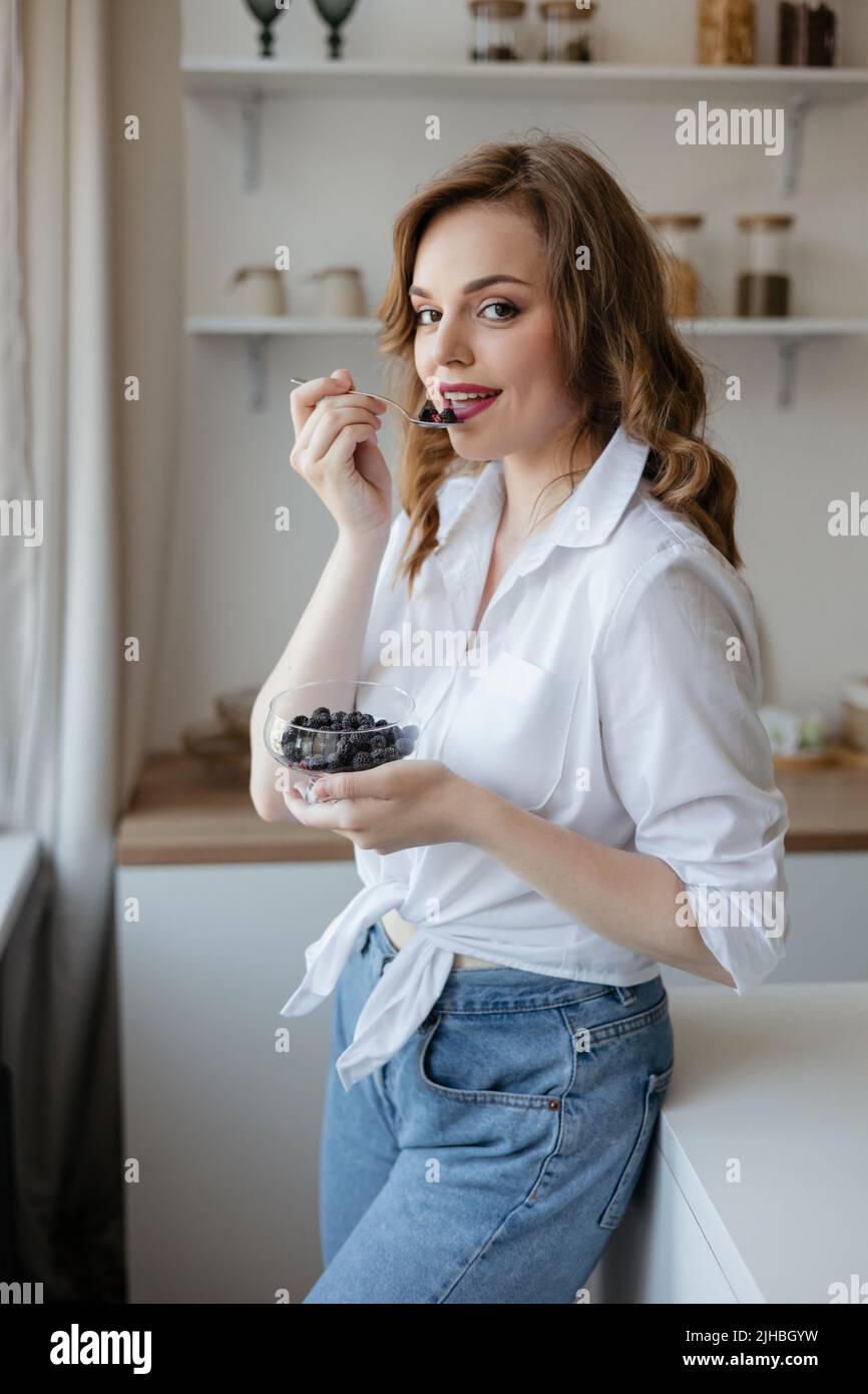 Pretty girl eating berries in the kitchen Stock Photo Alamy