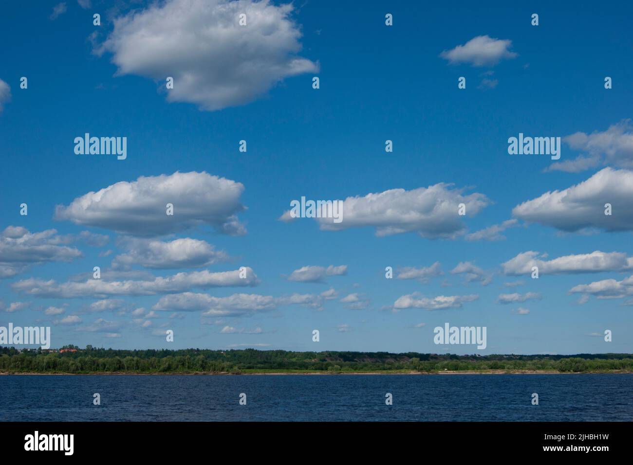 Deep cold ryokana in the north of Russia. The seasons are summer. A sandy beach with green bushes growing on it. White clouds in the blue sky - Stock Image