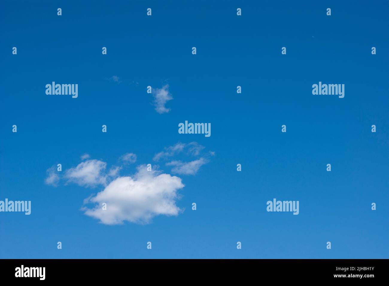 The horizontal photo is a blue sky with white fluffy clouds. Background, screensaver. Summer. Cloudy. Sunshine - Stock Image