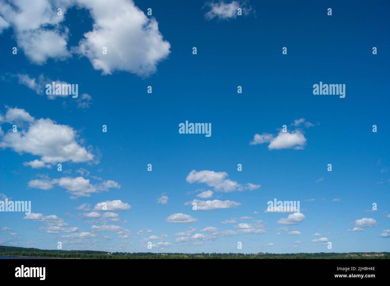 The horizontal photo is a blue sky with white fluffy clouds. Background, screensaver. Summer. Cloudy. Sunshine - Stock Image
