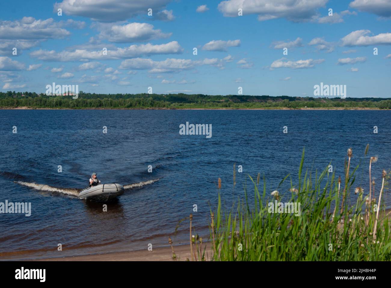 Deep cold ryokana in the north of Russia. The seasons are summer. A sandy beach with green bushes growing on it. White clouds in the blue sky - Stock Image