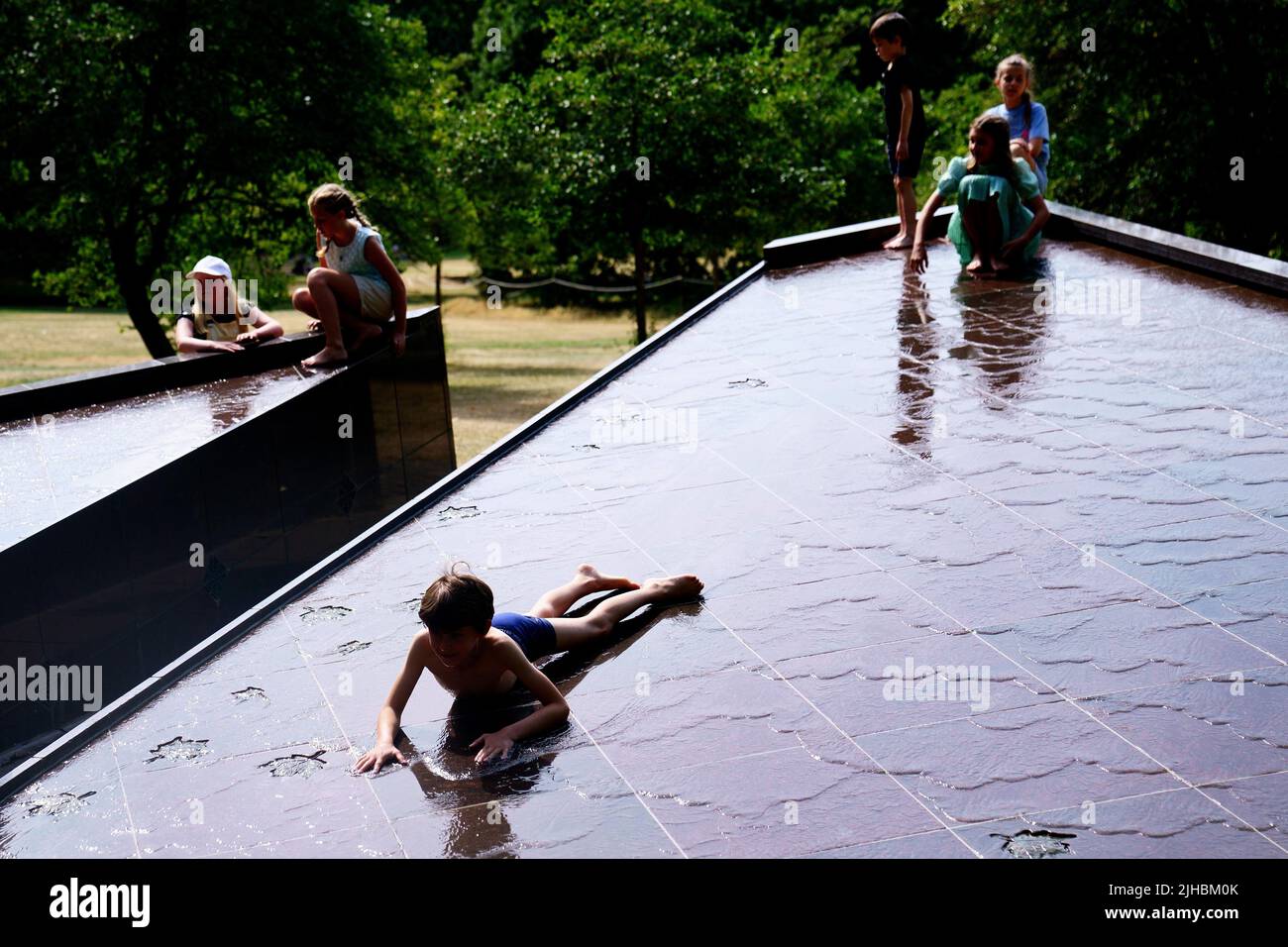 Young children play in the Canada Memorial fountain during warm weather in Green Park, central London. Temperatures are predicted to hit 31C across central England on Sunday ahead of record-breaking highs next week. Picture date: Sunday July 17, 2022. Stock Photo