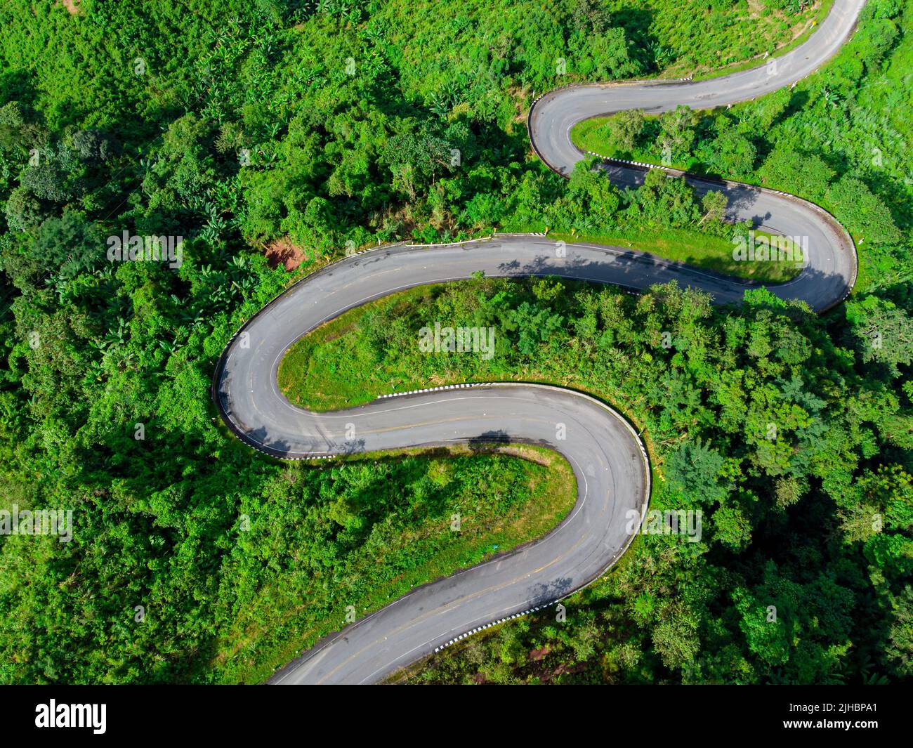 An aerial view of winding road in the scenic green woody terrain Stock ...