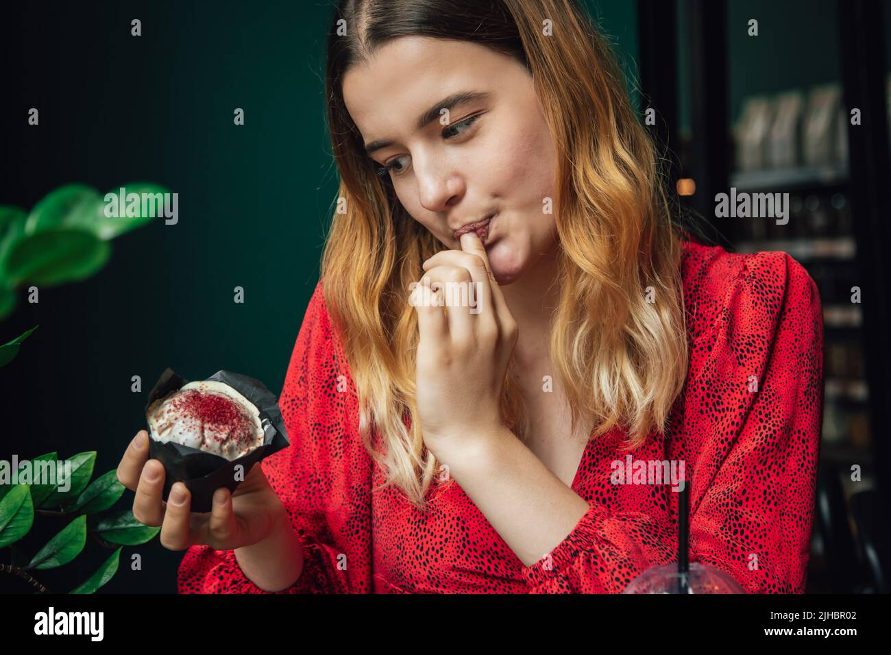 A young woman enjoys a raspberry muffin in a cafe Stock Photo - Alamy