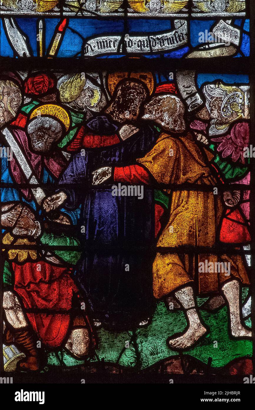 The Betrayal of Christ: vivid French stained glass depicting a scene from the Passion in which Judas Iscariot identifies Jesus to Roman soldiers by kissing him on the cheek.  The panel is in a window of 1511, created by the master glassmakers of Troyes, in the Église Saint-Rémi at Ceffonds, a village in the Haute-Marne department of the Champagne region in northeast France. Stock Photo