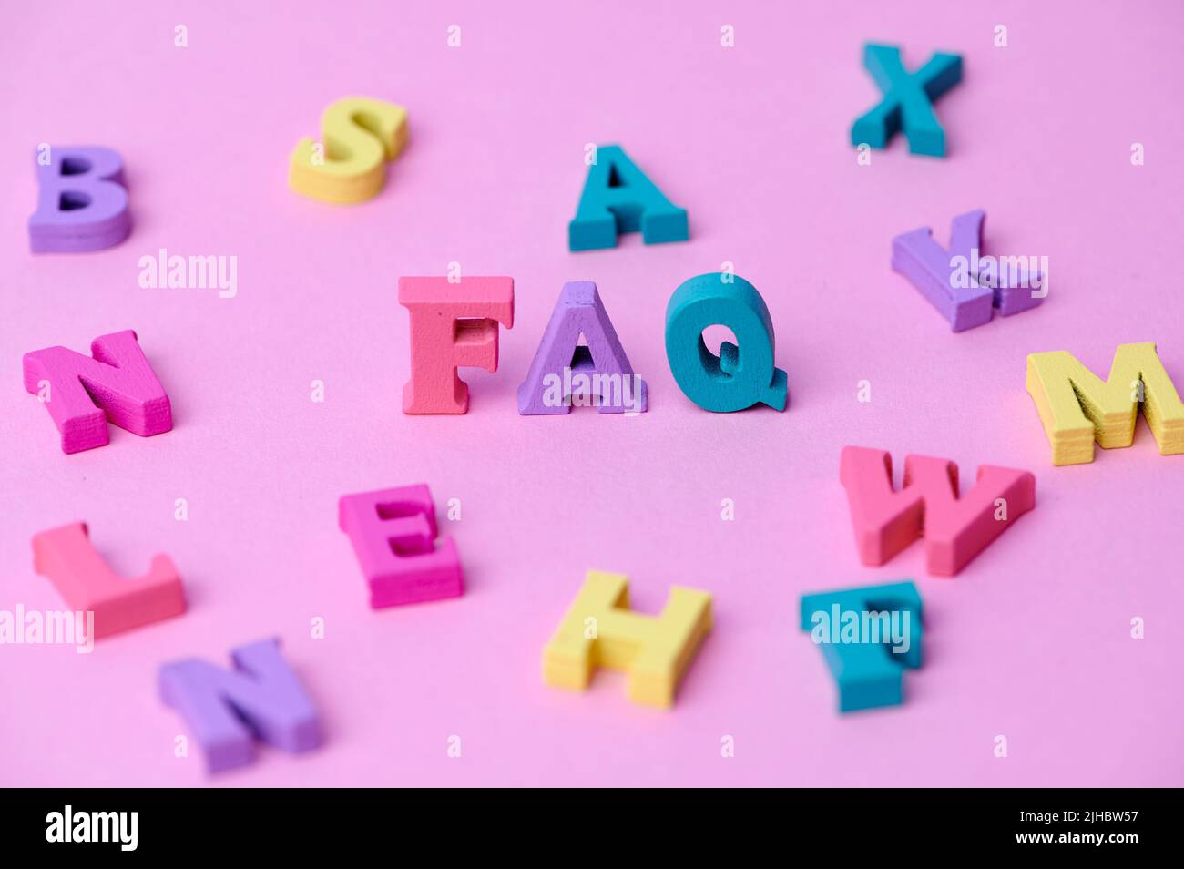 wooden colorful capital letters FAQ on pink background Stock Photo