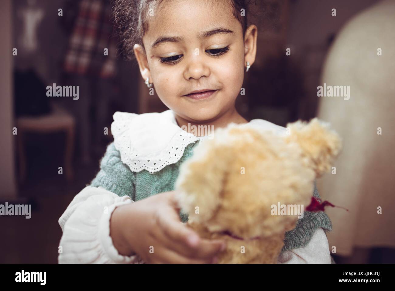 Adorable multiethnic little girl hugging her bear Stock Photo