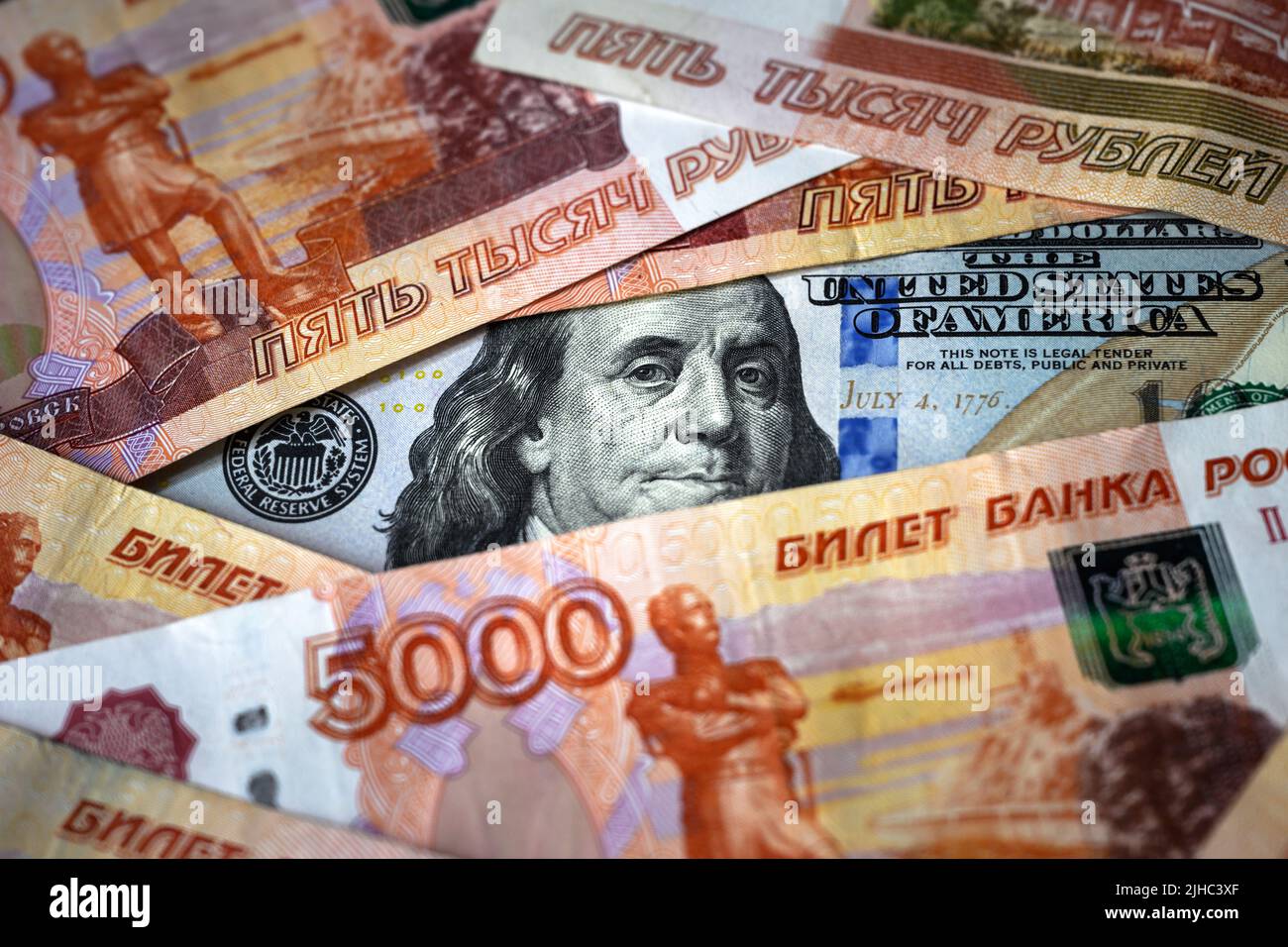 Russian ruble money vs US dollar, Franklin from 100 dollar bill watches through ruble banknote pile. Concept of USD, sanctions, currency, confrontatio Stock Photo