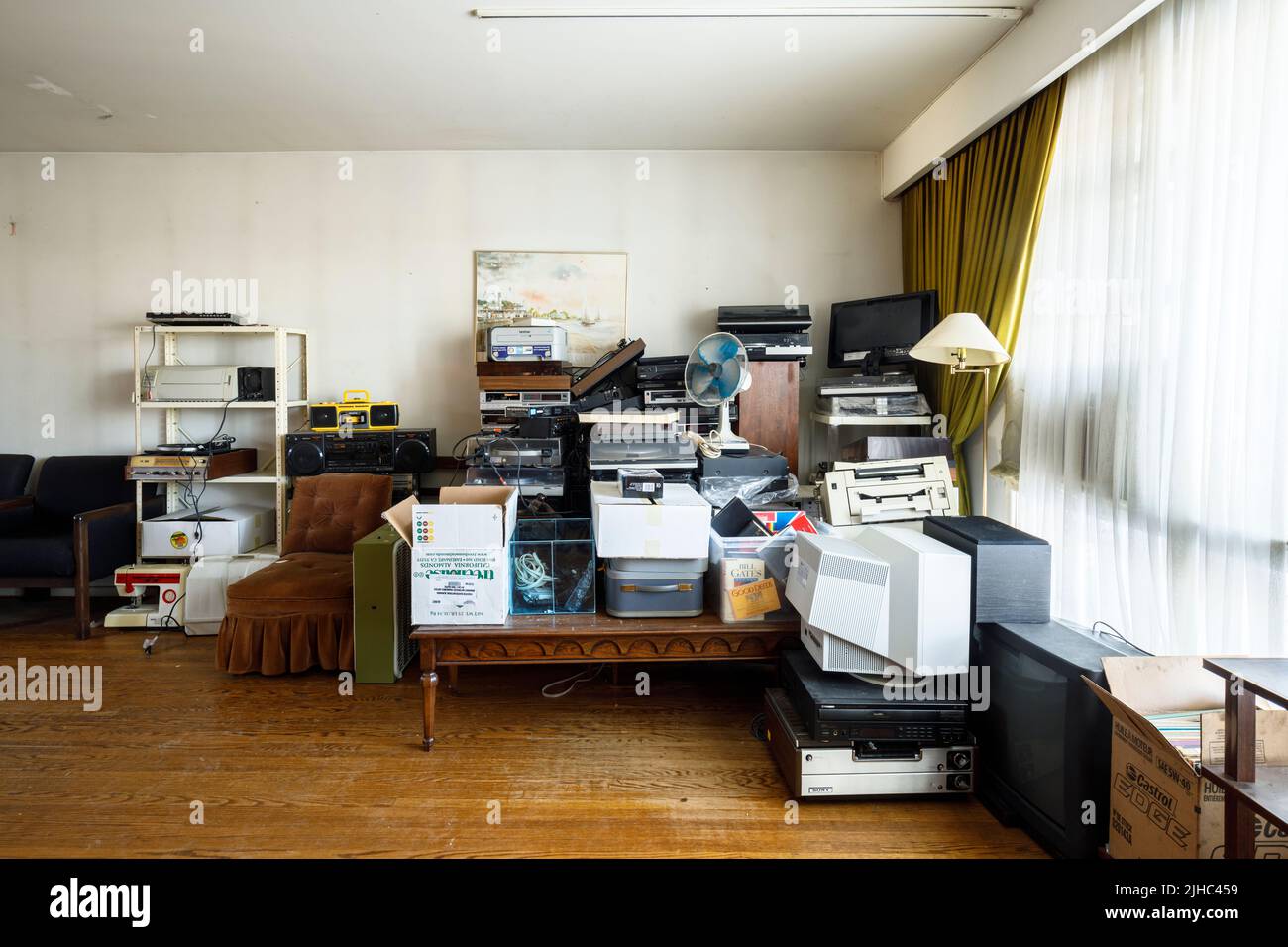 A cluttered mess of old electronics in a living room. Stock Photo