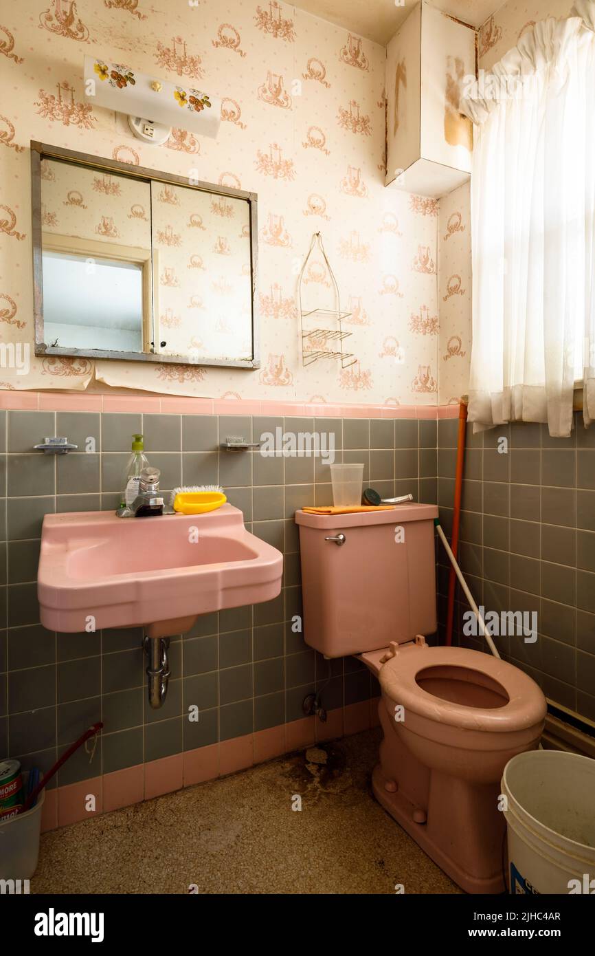 A 1950s washroom with tiled walls a pink toilet and sink. Stock Photo