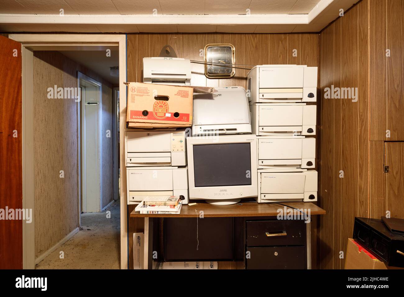 An outdated computer monitor and printers sitting on a retro desk. Stock Photo