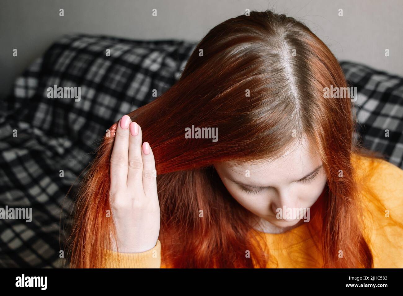 Young woman shows overgrown hair roots. Self care concept, hair