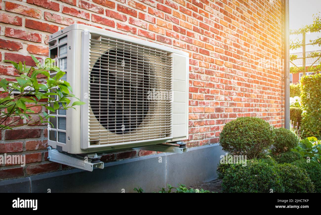 Air conditioning heat pump outdoor unit against brick wall Stock Photo