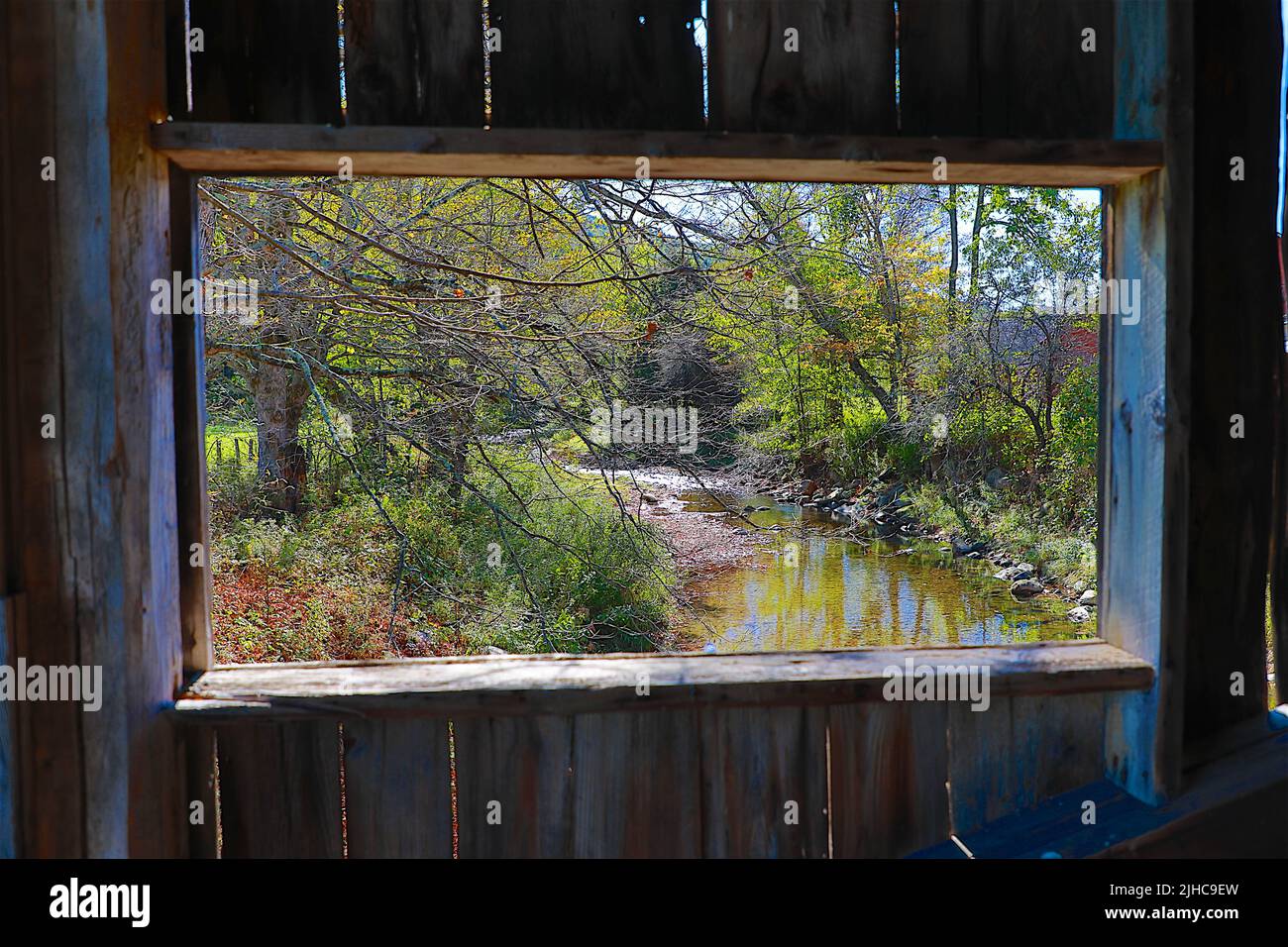 Scenes from Grafton, Vermont through the window of a covered bridge make this beautiful place scenic and historic as the creek passes below Stock Photo