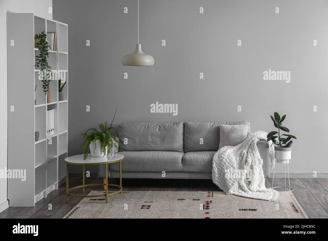 Interior of light living room with grey sofa, table and shelving unit ...
