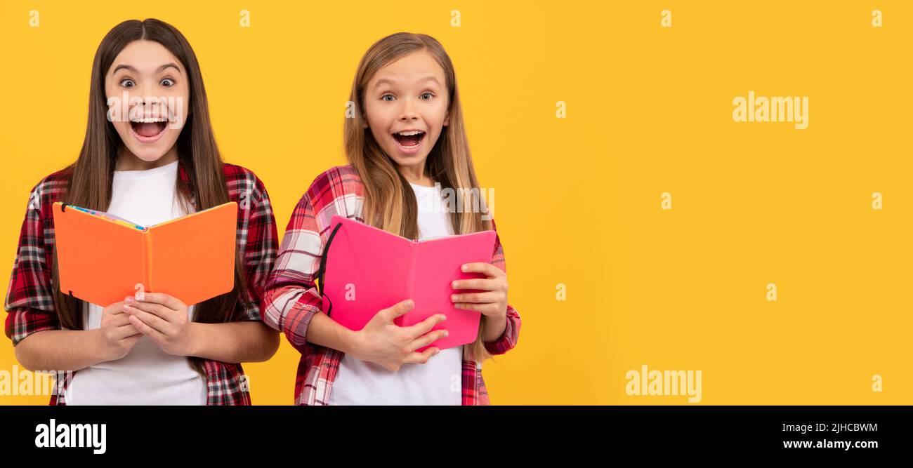 School girls friends. amazed kids in casual checkered shirt having fun reding books, amazement. Portrait of schoolgirl student, studio banner header Stock Photo