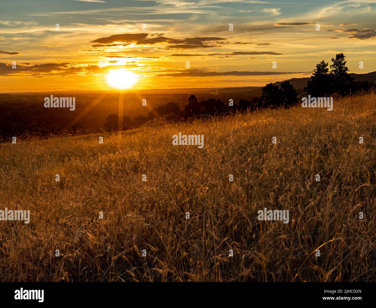 Summer sunset with clouds and grass covered hills Stock Photo