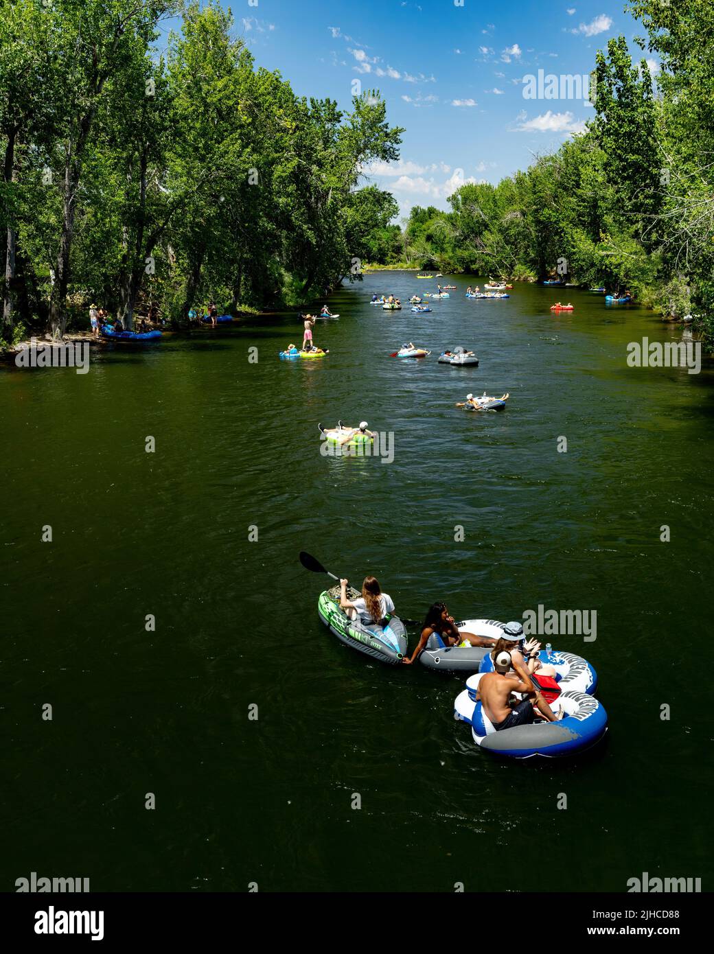 Tree lined Boise River in summer with tubers cooling off Stock Photo
