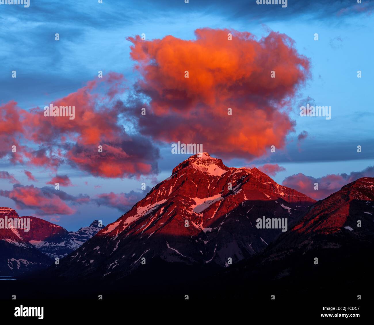 Warm color clouds float over a rocky mountain in Montana Stock Photo