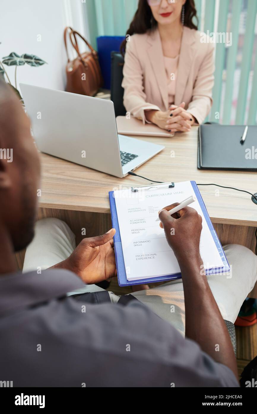 Applicant filling cv form during interview with human resources manager ...