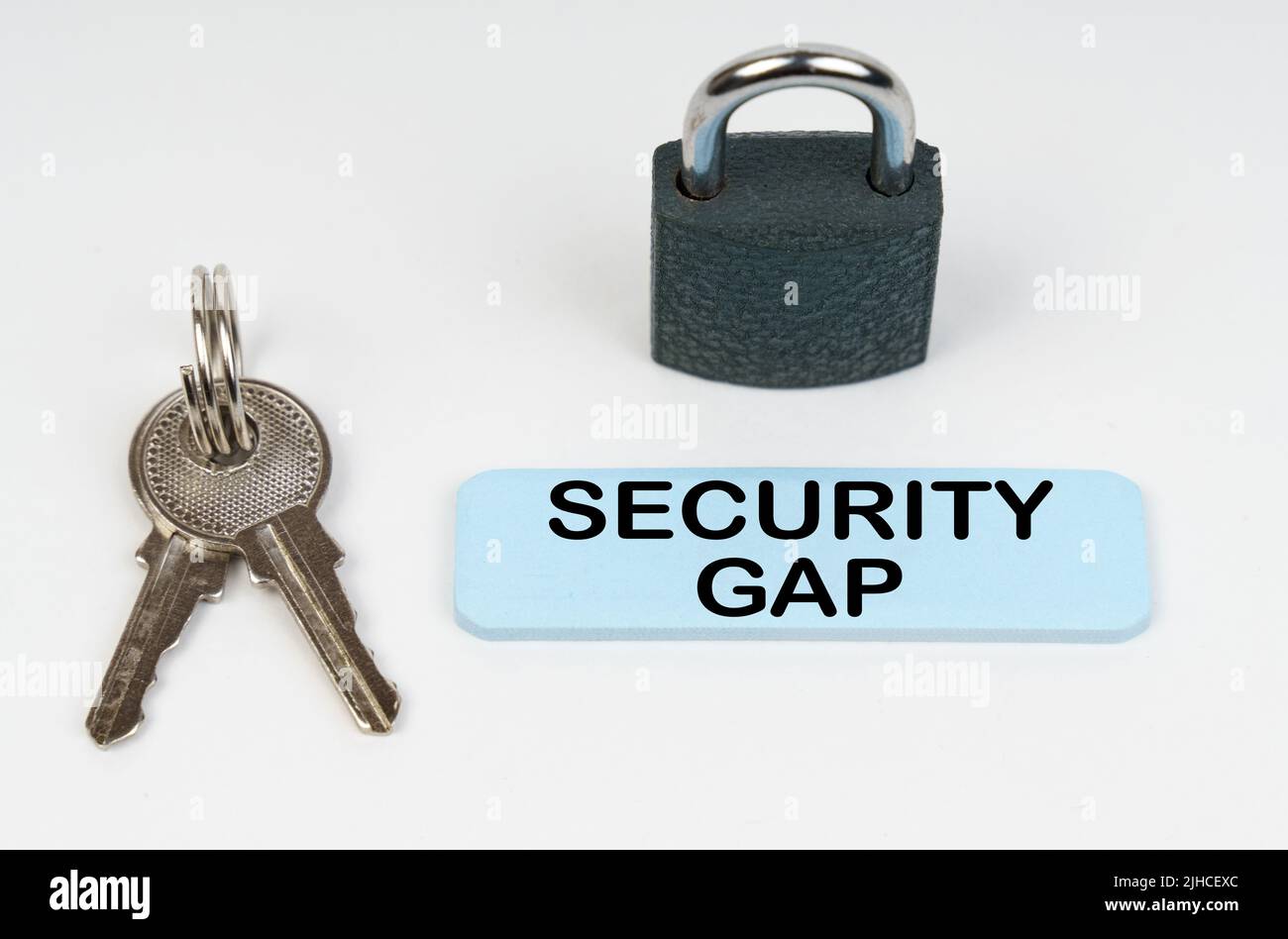 The concept of security in business. On a white surface there is a lock, keys and a blue sign with the inscription - Security gap Stock Photo