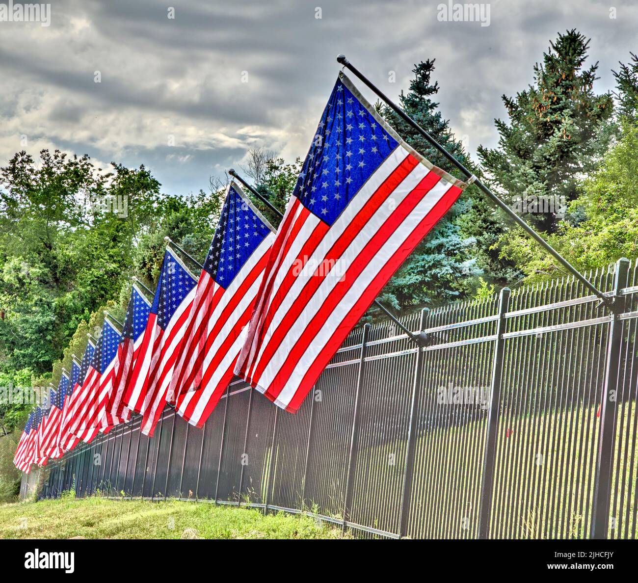 American flags hang from flag poles attached to a steel fence in