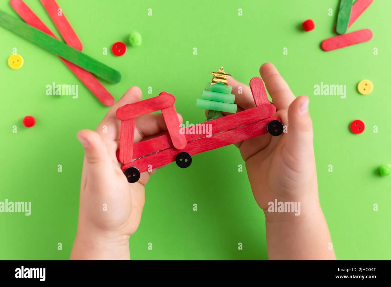 Red car with fir tree made from wooden sticks. Handmade. Project of children's creativity, handicrafts, crafts for kids. Child's hands Stock Photo