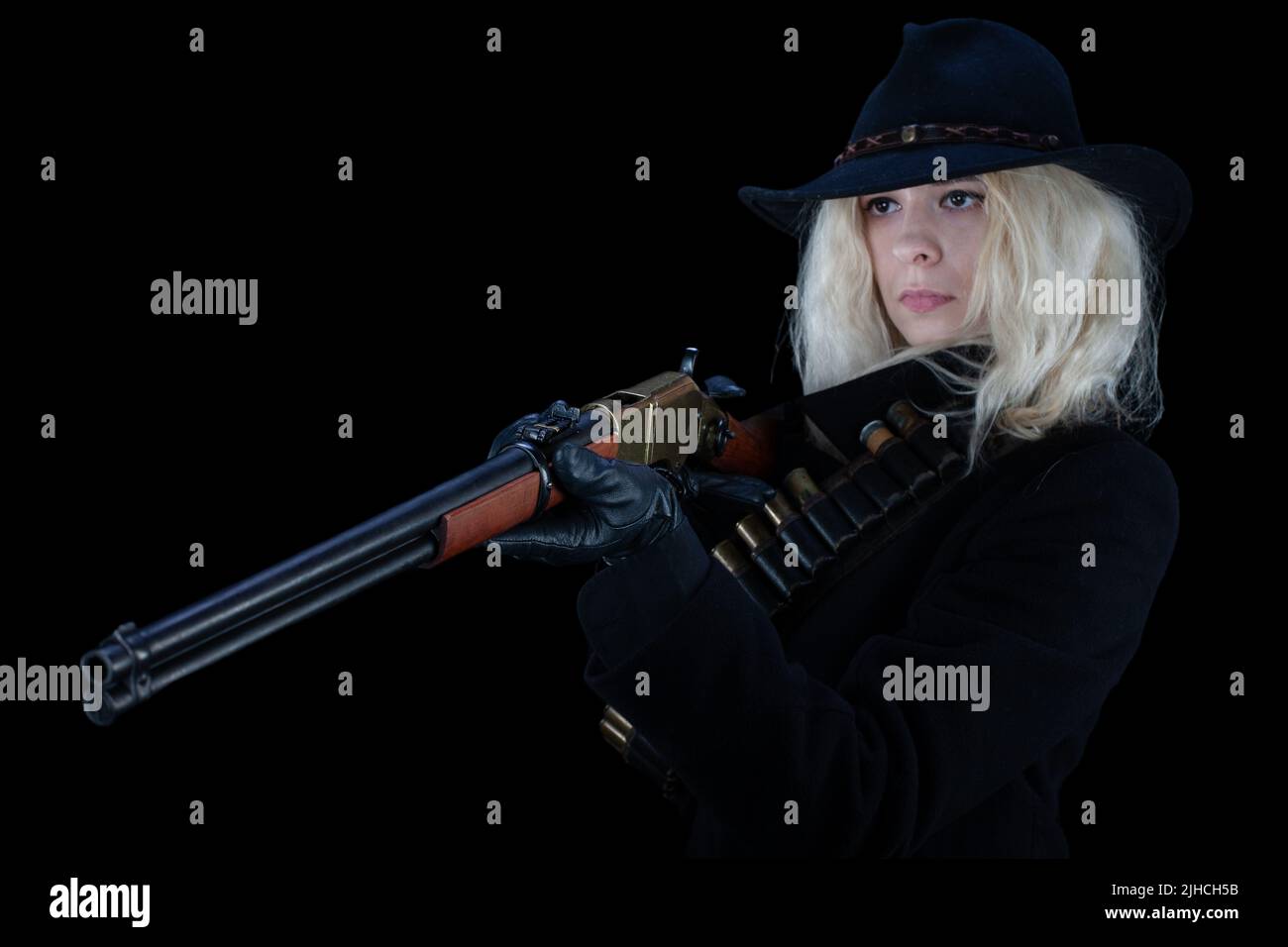old west blonde girl wearing black hat with rifle on black background Stock Photo