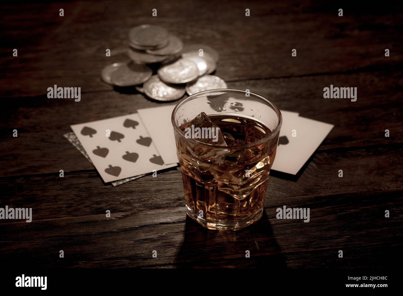 Wild west gambling. Dead man's hand, silver coins and whiskey shot. Two-pair poker hand consisting of the black aces and black eights, held by Old Wes Stock Photo