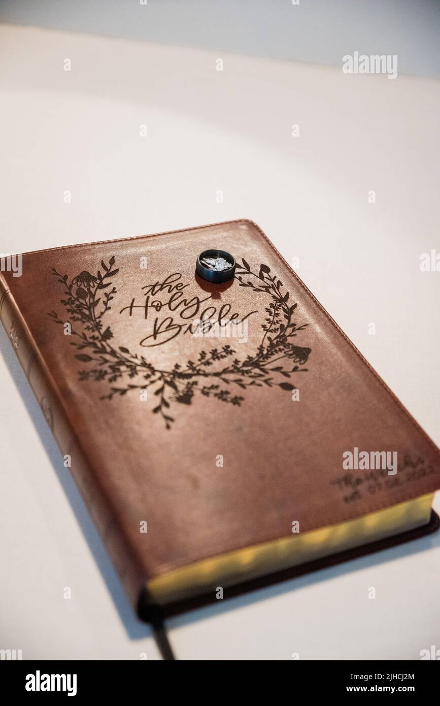 A vertical shot of rings on a Holy Bible with golden paper edges Stock ...