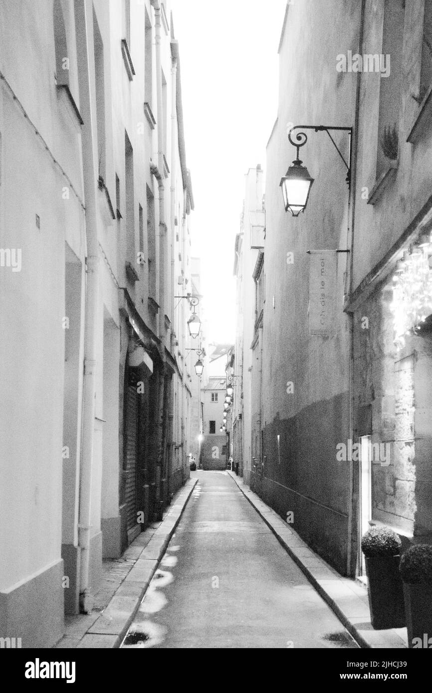 A vertical grayscale shot of a narrow street between buildings Stock ...