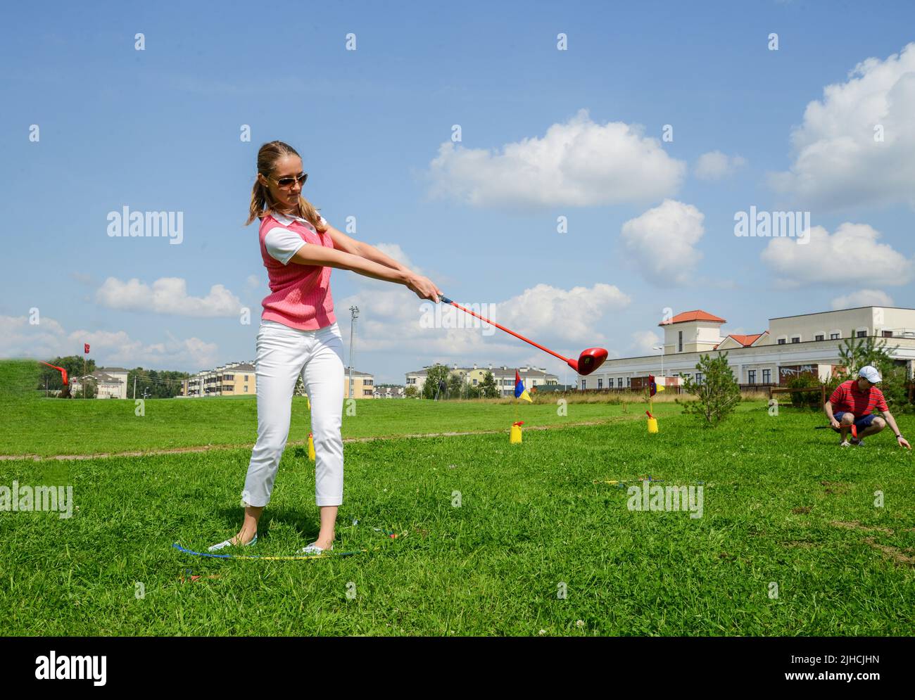 08-10-2013 Moscow Oblast, russia. Cute young lady (student) training strikes with golf club ( sand wedge) . Green grass on the field.   golf field  fo Stock Photo