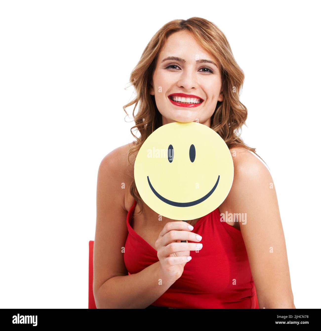 Give the world your widest smile. A charismatic young woman holding a paddle with a smiley face on it. Stock Photo