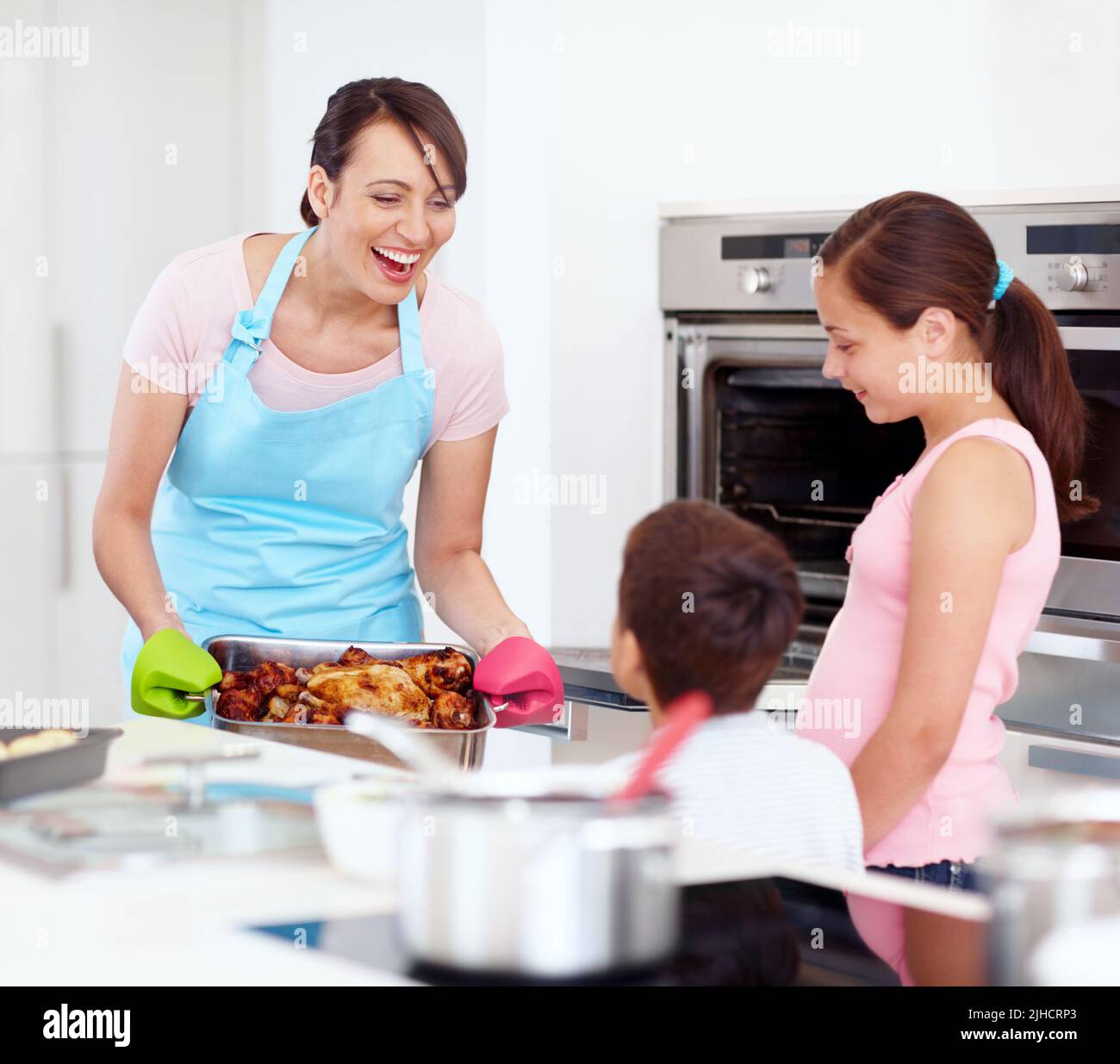 Soul food. An excited mother and her happy children cooking a roast together in the kitchen. Stock Photo