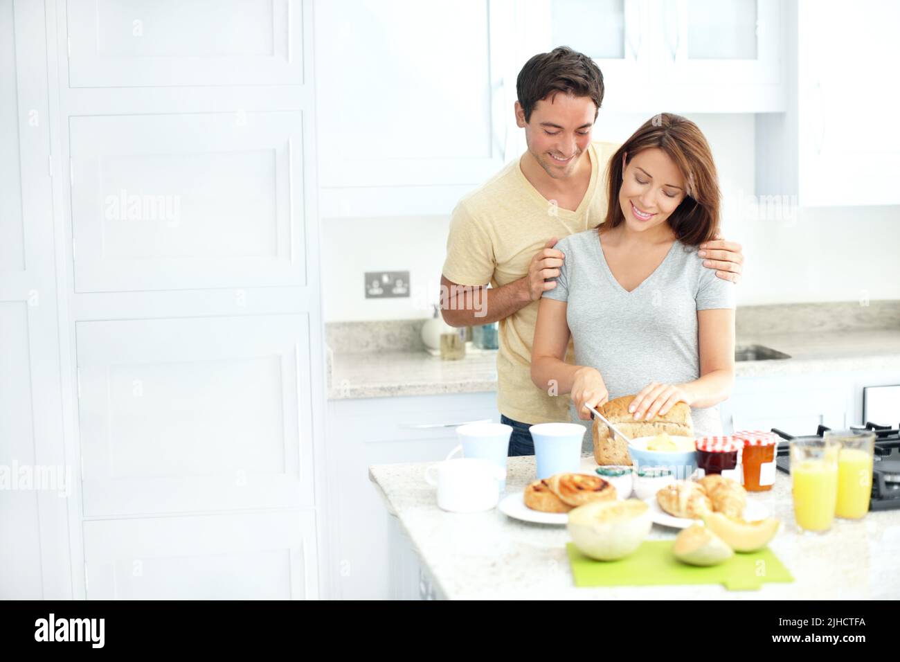 The most important meal of the day. Young pregnant woman preparing food in the kitchen with her husband. Stock Photo