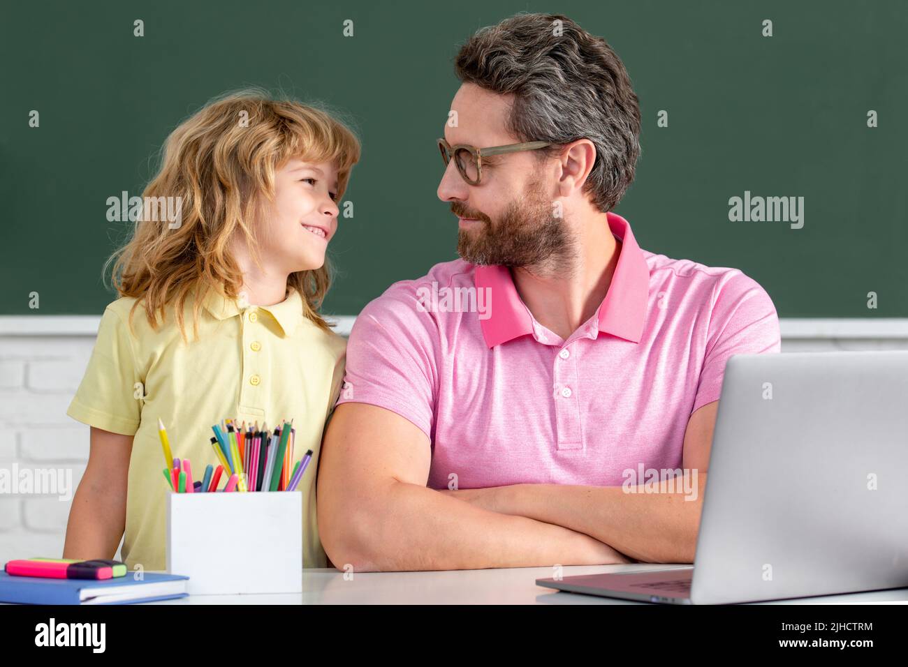 Elementary school boy in classroom on lesson. Teacher explaining to