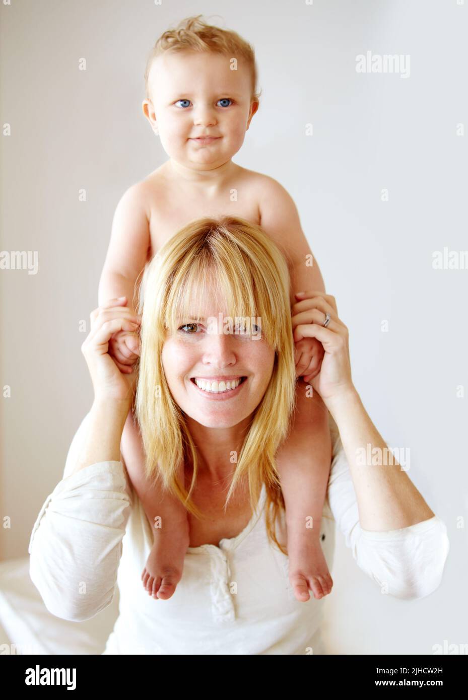 Proud of her healthy boy. Smiling mother with her baby boy sitting on her shoulders. Stock Photo