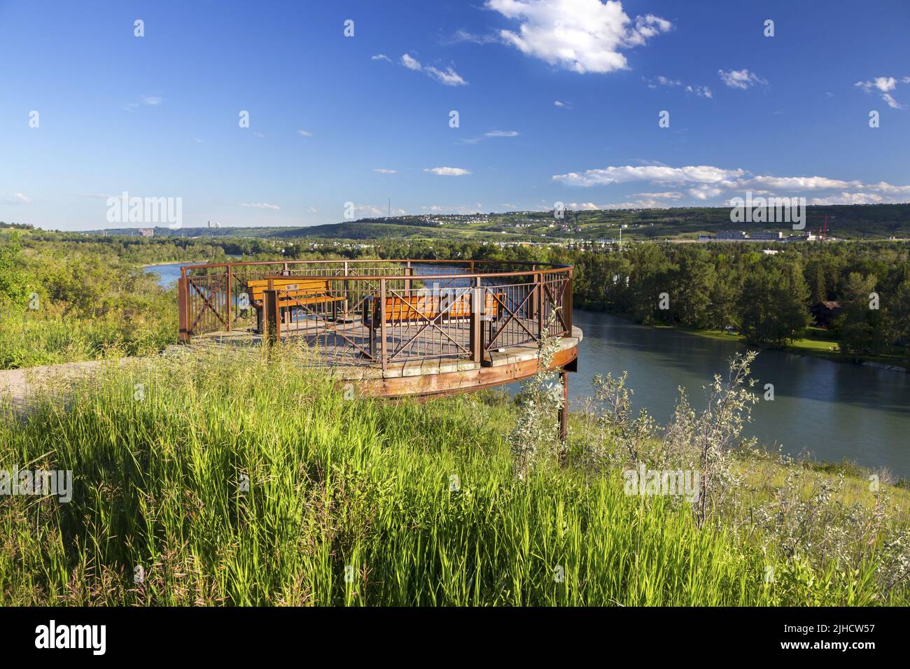 Observation Platform at East Bowmont Urban Recreation Park above Bow River with Green Prairie Grass and Distant Calgary, Alberta City Skyline Stock Photo