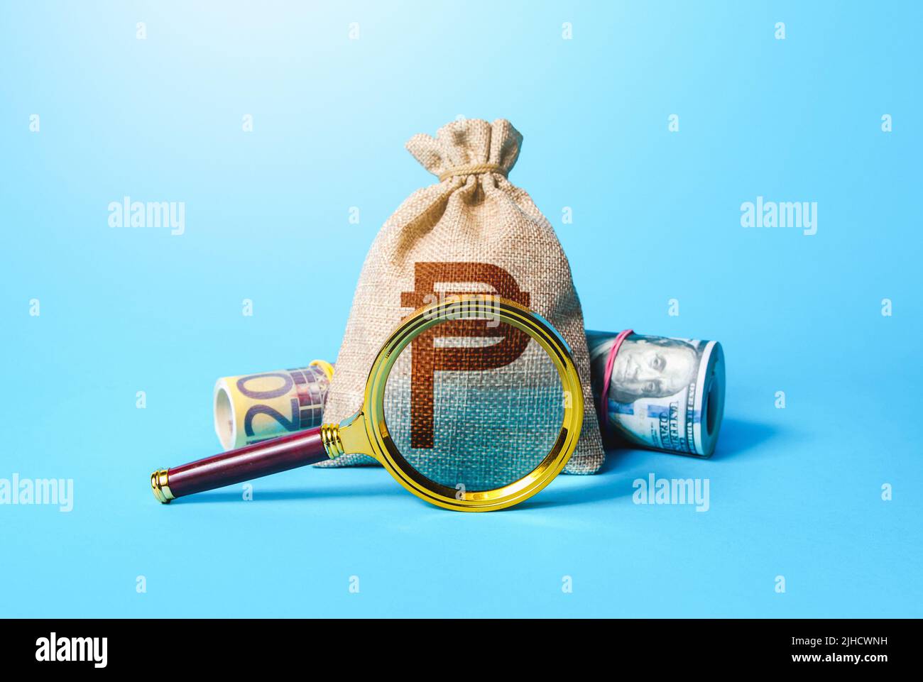Philippine peso money bag and magnifying glass. Investigating capital origins. Deposit or loan terms and conditions. Find investment funds for busines Stock Photo