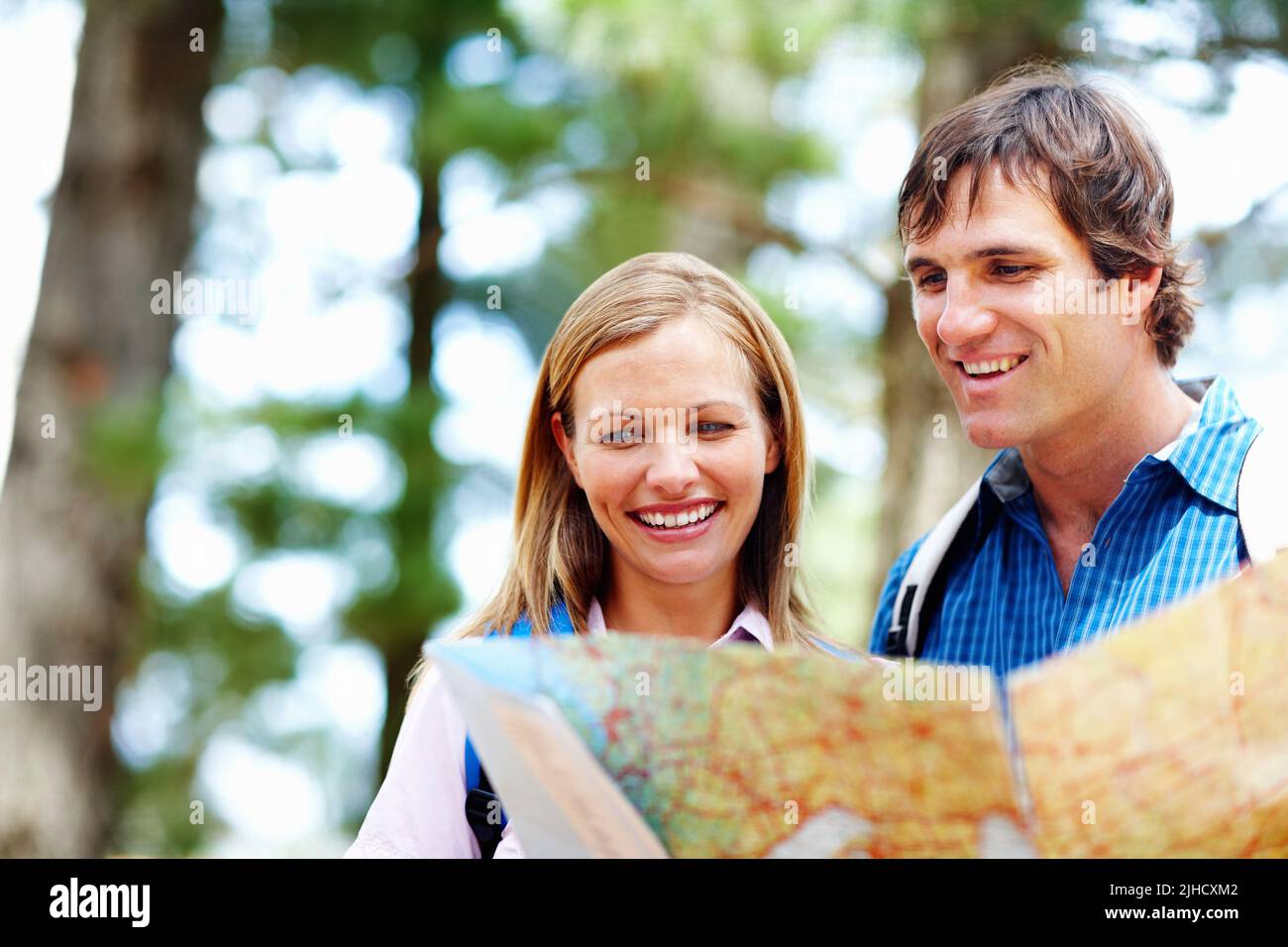 Couple taking a look at map. Couple with backpack taking a look at map and smiling. Stock Photo